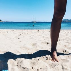 Low section of man on beach against clear sky