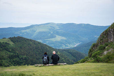 Rear view of couple sitting against mountain range