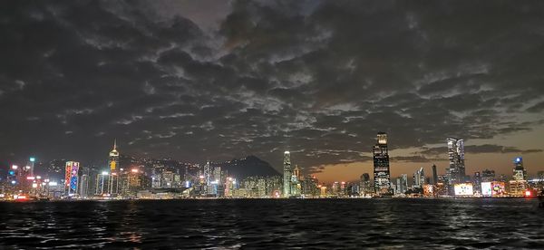 Illuminated buildings by city against sky at night