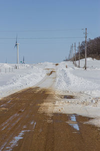 Electricity pylons on land against clear sky during winter