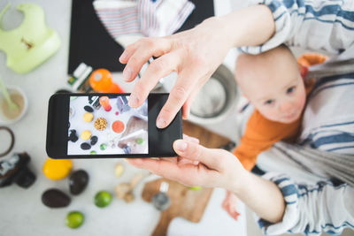 High angle view of female influencer food blogging with baby girl in kitchen