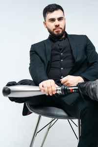 Young man sitting on chair against white background