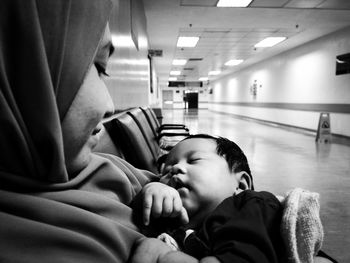 Side view of woman with baby girl sitting on bench in hospital