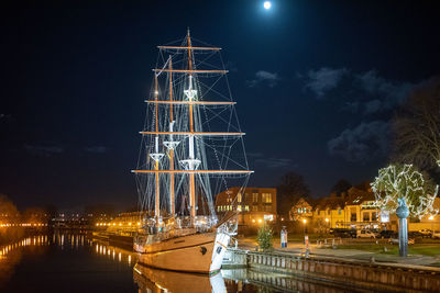 Illuminated bridge over river against sky at night