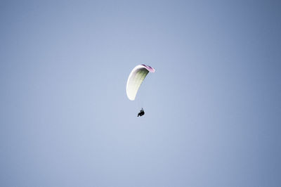 Low angle view of person paragliding against clear sky