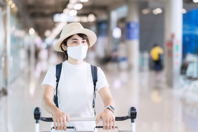 Woman wearing mask looking away while standing at airport
