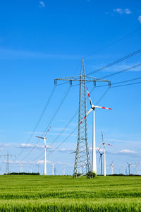 Windmills on field against sky