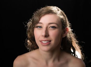 Portrait of shirtless young woman against black background