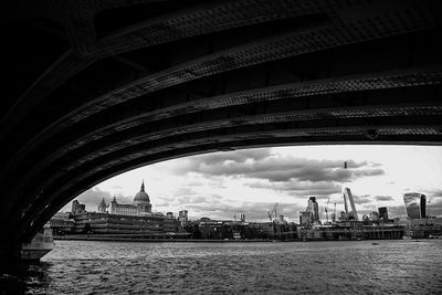 Arch bridge over thames river by st paul cathedral against sky