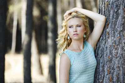 Portrait of a beautiful young woman with tree trunk in forest