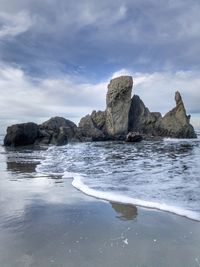 Rock formation on beach against sky