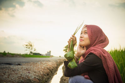 Young woman wearing hijab looking away against sky