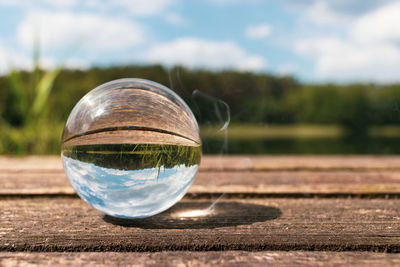 Close-up of glass ball on field against sky