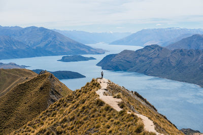 Man hiking amongst mountain views from the roys peak trail, new zealand