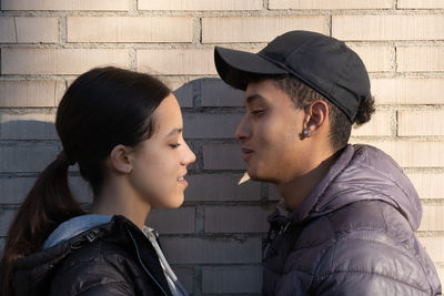 Side view of young man looking away against wall