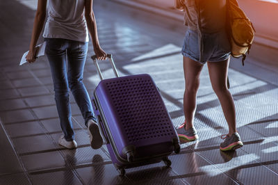 Low section of women walking with luggage at airport