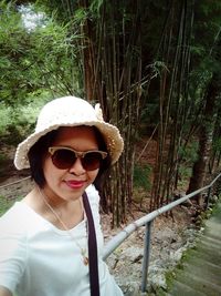 Portrait of young woman wearing sunglasses in forest