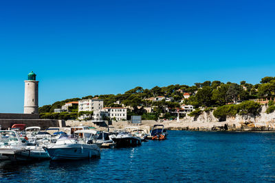 Boats in sea against clear blue sky