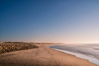 Scenic view of beach against clear blue sky