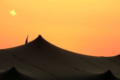 Low angle view of silhouette mountain against orange sky