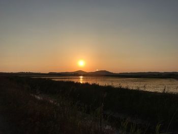 Scenic view of field against clear sky during sunset