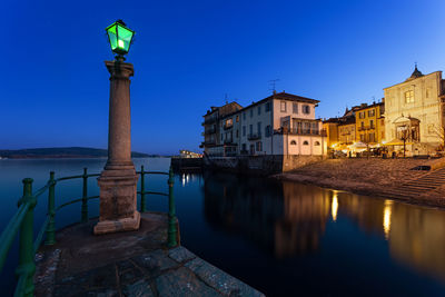 Illuminated street light against blue sky at night