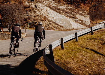 Rear view of man riding bicycle on road