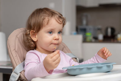 Portrait of cute baby boy eating food at home