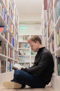 Side view of man sitting on chair at library