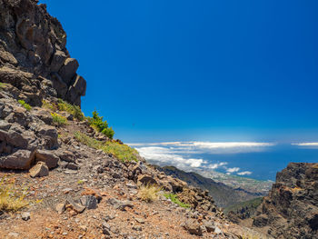 Scenic view of rocky beach against blue sky