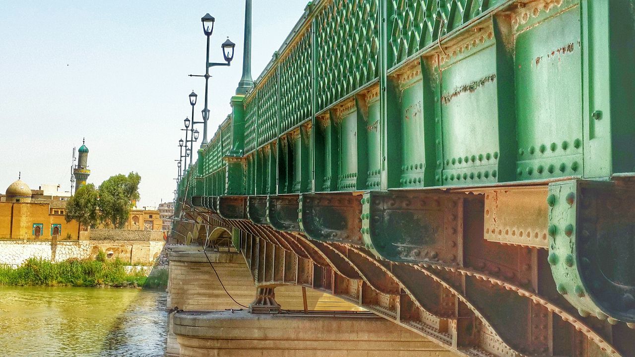 built structure, architecture, building exterior, connection, clear sky, transportation, railing, bridge - man made structure, day, sky, the way forward, outdoors, no people, water, diminishing perspective, city, text, building, in a row, river