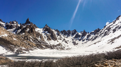 Scenic view of snowcapped mountains against blue sky