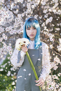 Portrait of beautiful young woman standing by cherry blossom