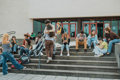 Group of friends sitting on stairs against building