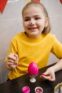 Cheerful girl coloring easter eggs, soiled nose