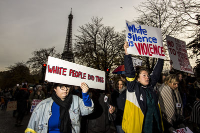 Group of people standing by sign board against trees