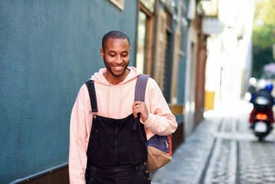 Young man looking away while standing on street in city