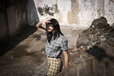 Young woman standing against wall outdoors