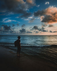 Rear view of man on beach against sky during sunset