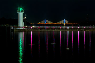 Illuminated bridge over river at night