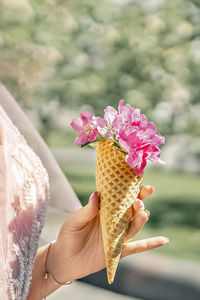 Flowers in a waffle cone in a woman's hand. the flowering of fruit trees in the garden