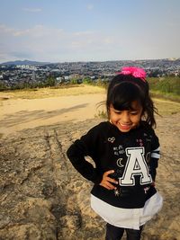 Smiling girl standing on land against sky