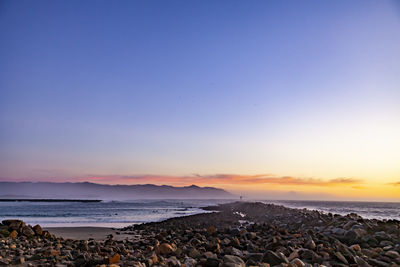 Scenic view of pacific ocean against a clear sky at sunset.