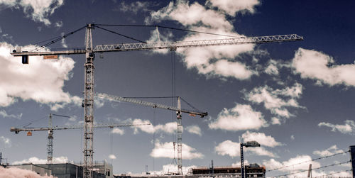 Low angle view of crane against cloudy sky