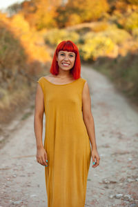 Portrait of smiling woman standing on dirt road