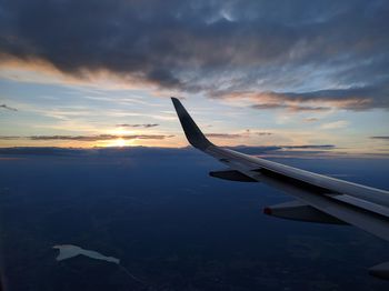 Close-up of airplane wing against sky during sunset