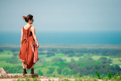 Rear view of young woman looking at sea while standing on observation point against sky