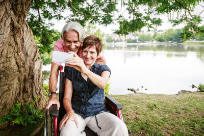 Portrait of happy friends sitting by lake