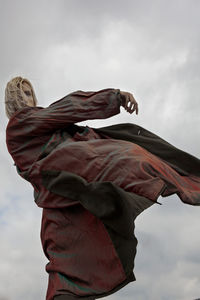 Low angle view of man levitating against cloudy sky