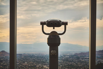 Coin-operated binoculars against sky during sunset